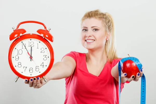 Счастливая женщина держит часы, яблоко и измерительную ленту — стоковое фото