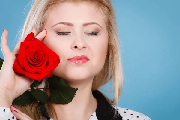 Жінка тримає червону квітку троянди на синьому — стокове фото
