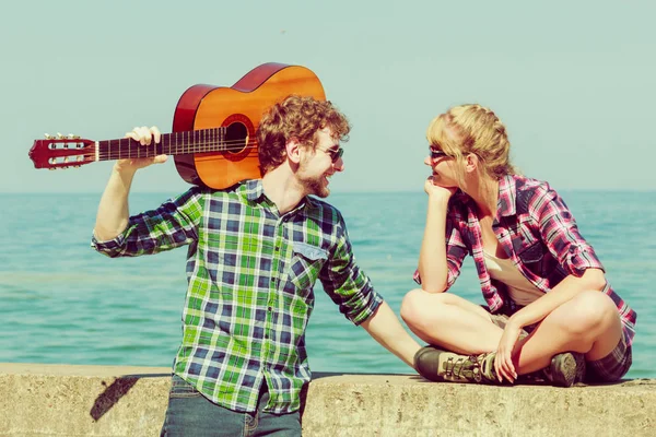 Joven tocando la guitarra a su novia junto al mar — Foto de Stock