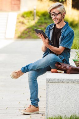 Hipster gülümseyen adam kenarında oturan tablet ile
