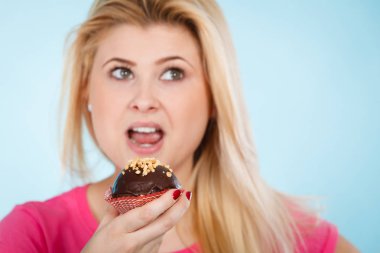 Çikolatalı kek tutan kadın ısırmak üzere.
