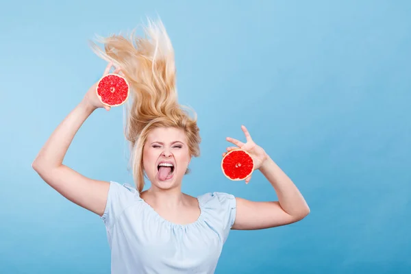 Woman holding red grapefruit having crazy windblown hair — Stock Photo, Image