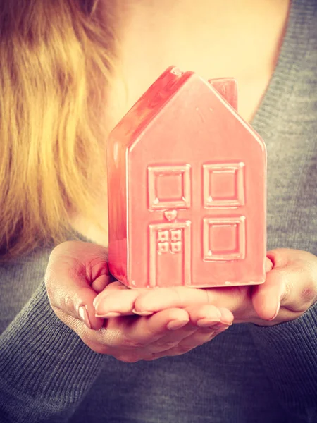 Person holding house model.