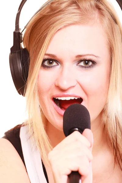 Woman singing to microphone wearing headphones — Stock Photo, Image