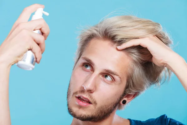 Hombre aplicando spray cosmético a su cabello — Foto de Stock