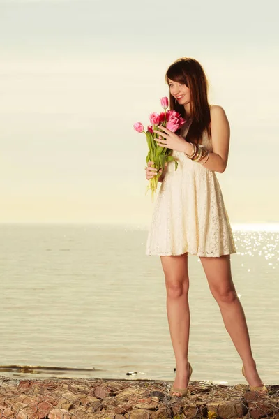 Belle femme tenant bouquet de fleurs sur la plage — Photo