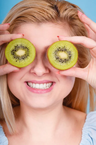 Woman holding green kiwi fruit like eyeglasses — Stock Photo, Image