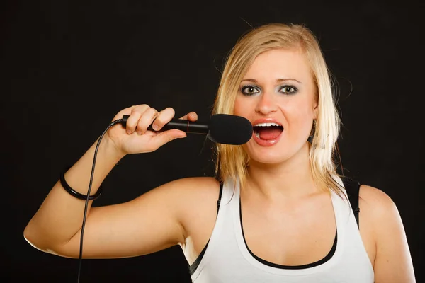 Блондинка поет под микрофон — стоковое фото