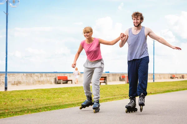 Pareja joven patinando en parque tomados de la mano . — Foto de Stock