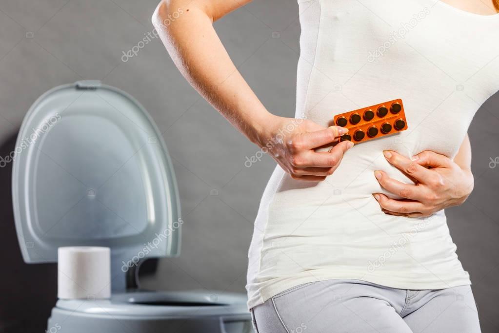 Woman suffer from belly pain holds pills in toilet