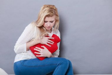 Holding sıcak su şişesi kadının duygu mide krampları