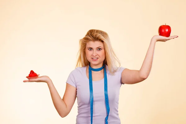 Woman choosing between apple and sweet cupcake — Stock Photo, Image