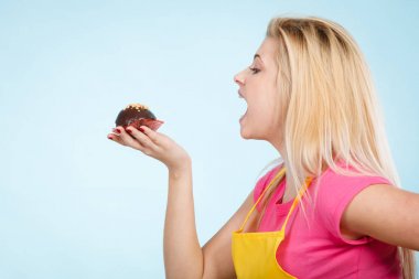 Çikolatalı kek tutan kadın ısırmak üzere.