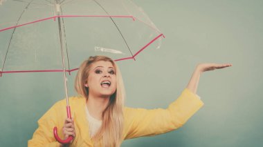 Hava kontrol şemsiye tutan yağmurluk giyen kadın