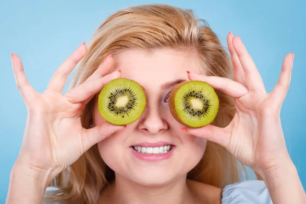 Woman holding green kiwi fruit like eyeglasses — Stock Photo, Image