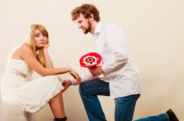 Uomo dando infelice donna caramelle mazzo di fiori . — Foto Stock