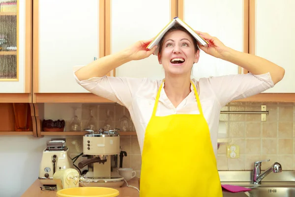 Funny housewife with cookbook on head — Stock Photo, Image
