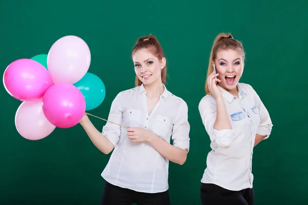 Two girls with mobile phone and balloons — Stock Photo, Image