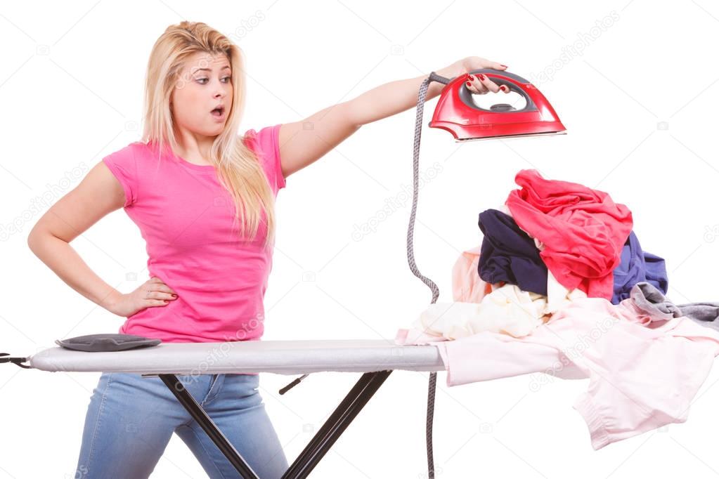 Shocked woman holding iron about to do ironing