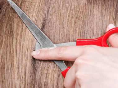 Sarı saçlı kırmızı makaslar. Yakın çekim.