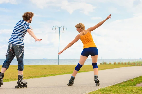 Pareja joven en patines de ruedas montando al aire libre — Foto de Stock