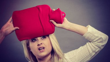 Kırmızı sıcak su şişesi üzerinde kafa tutan kadın