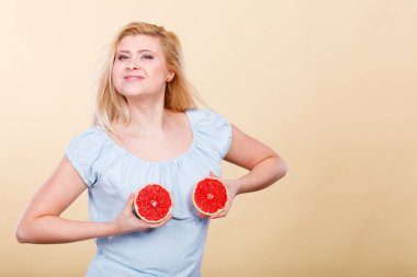 Kırmızı greyfurt meme üzerinde tutan kadın