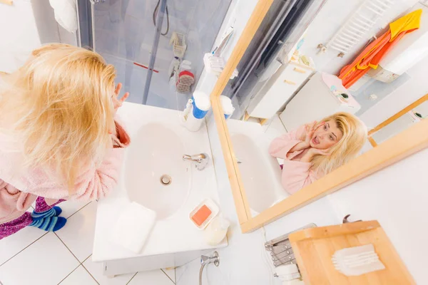 Frau blickt auf ihr sehr wirres blondes Haar — Stockfoto