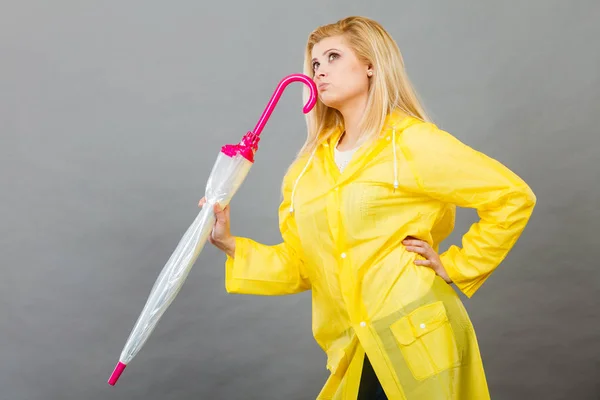 Thinking woman wearing raincoat holding closed umbrella — Stock Photo, Image