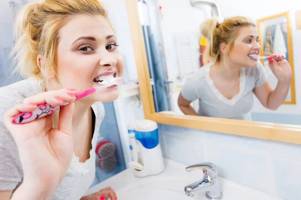 Женщина чистит зубы в ванной комнате — стоковое фото