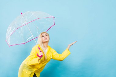 Hava kontrol şemsiye tutan yağmurluk giyen kadın