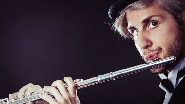 Элегантно одетый музыкант играет на флейте — стоковое фото