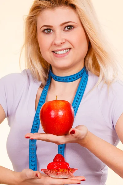 Woman with measuring tape choosing what to eat — Stock Photo, Image