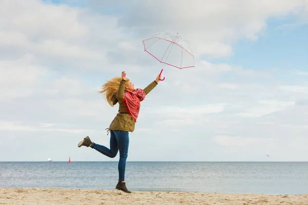 Kobieta, skoki z przezroczystym parasol na plaży — Zdjęcie stockowe