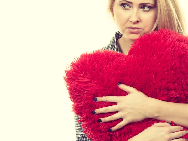 Ragazza triste che tiene grande cuscino rosso a forma di cuore — Foto Stock