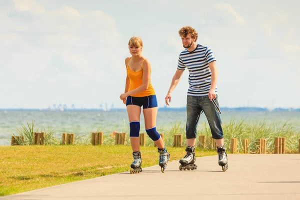 Pareja joven en patines de ruedas montando al aire libre — Foto de Stock