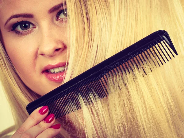 Mulher loira escovando seu cabelo longo com pente — Fotografia de Stock