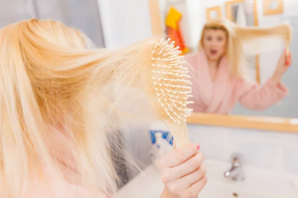 Shocked woman wearing dressing gown brushing her hair