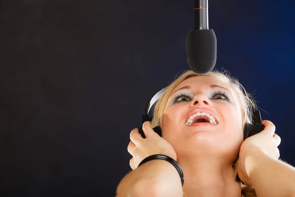 Kvinnan som sjunger till mikrofon bär hörlurar i studio — Stockfoto