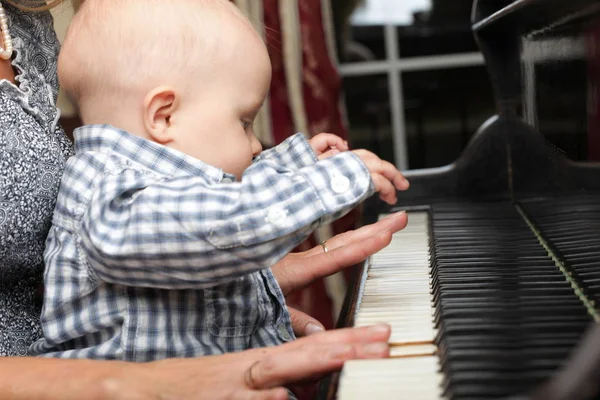 Beautiful little baby boy plays piano — Stock Photo, Image