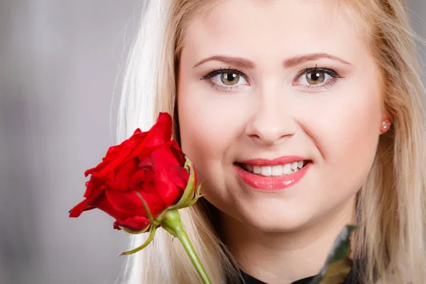 Kvinna med röd ros nära ansikte leende — Stockfoto