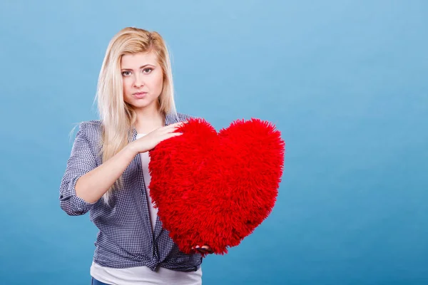 Mujer triste sosteniendo almohada roja en forma de corazón — Foto de Stock