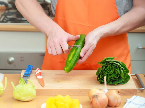 Man preparing vegetables salad peeling cucumber — Stock Photo, Image