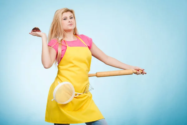 Mulher segurando cupcake, rolo, escorredor vestindo avental — Fotografia de Stock