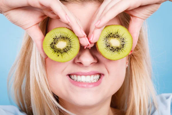 Woman holding green kiwi fruit like eyeglasses — Stock Photo, Image