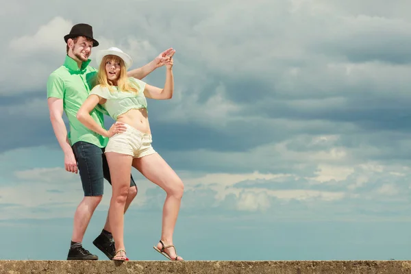 Pareja joven mirando hacia arriba mostrando con el dedo al aire libre — Foto de Stock