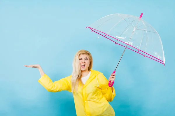Woman wearing raincoat holding umbrella checking weather — Stock Photo, Image