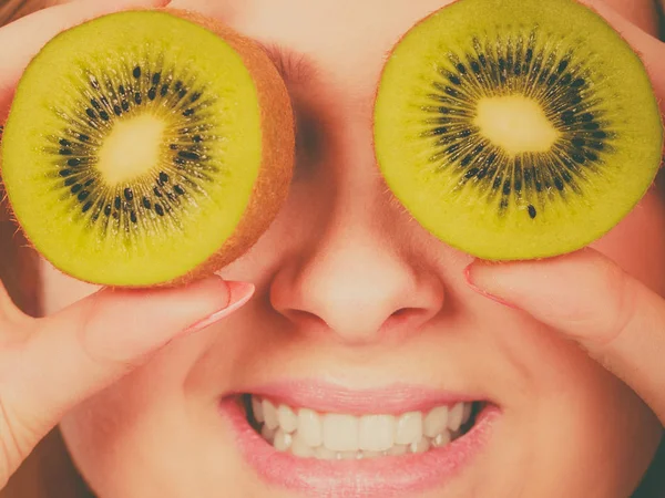 Woman holding green kiwi fruit like eyeglasses — Stock Photo, Image