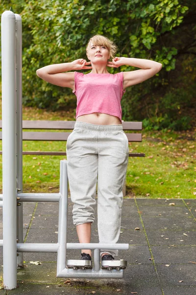 Mujer activa haciendo ejercicio en backtrainer al aire libre . — Foto de Stock