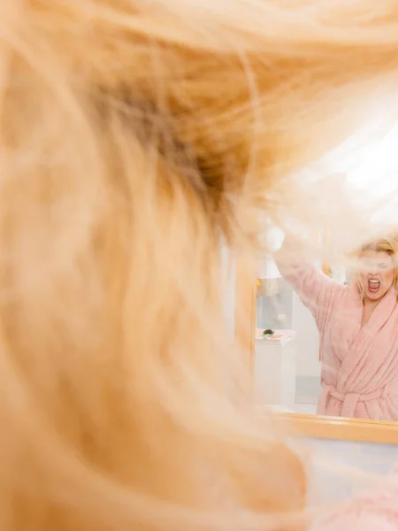 Frau blickt auf ihr sehr wirres blondes Haar — Stockfoto